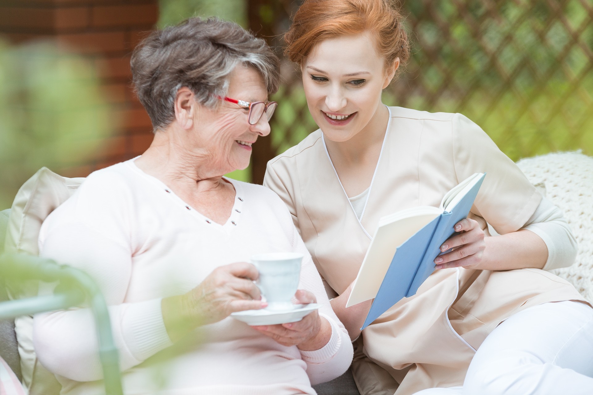 Senior woman holding a cup of coffee and talking to her nurse